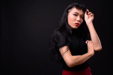 Fototapeta na wymiar Young beautiful Asian transgender businesswoman against black background