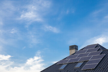 Fototapeta na wymiar Saving energy concept. Solar panel close up on a house roof on cloudy sky background.