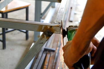 The technician uses a electric grinding wheel on steel structure Sparks  the workpiece to be completed.