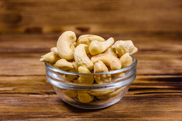 Glass bowl with raw cashew nuts on a wooden table