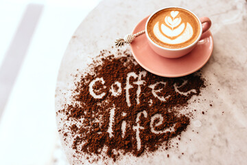 Pink cup of cappuccino on marble table background. Love latte art on the top of it.