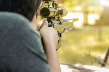 Military sniper with his precising sniper rifle aiming through scope and shooting in the shooting range 