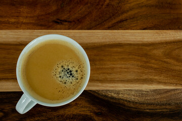 A cup of coffee on a wooden table.