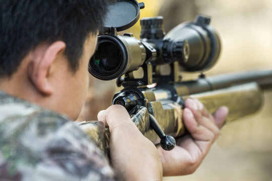 Military sniper with his precising sniper rifle aiming through scope and shooting in the shooting range 