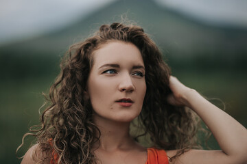 Close-up photo of a girl in an orange dress against a background of mountains, portrait photo of a young girl