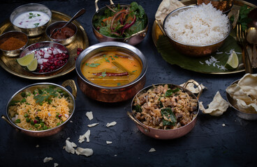 South Indian vegetarian food served on traditional platters  and trays, black background