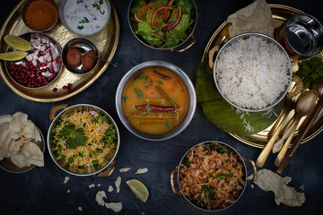 South Indian vegetarian food served on traditional platters  and trays, black background