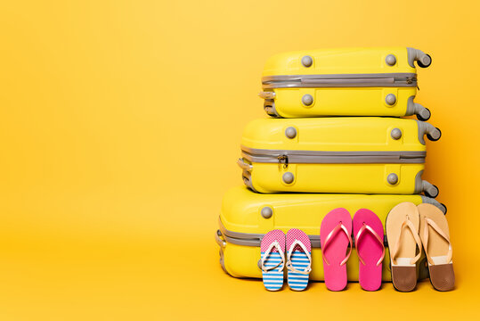 travel bags with family flip flops isolated on yellow