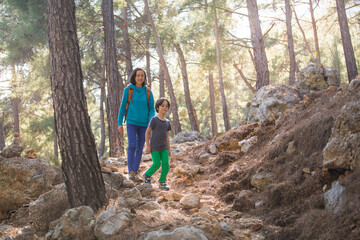 A woman walks with her son through the forest.