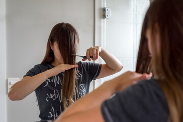 Woman with long brown hair cutting her own bangs