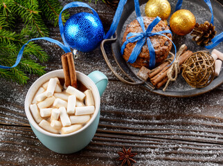 Fototapeta na wymiar Flat lay Christmas background of blue mug with hot chocolate and marshmallows, spruce branch and tray with gingerbread cookies on wooden table