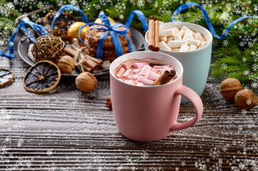 Christmas background of two mugs of hot chocolate with marshmallows, spruce branch and tray with gingerbread cookies on wooden table