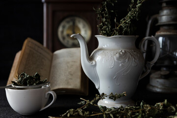 Fototapeta na wymiar Tea Party. Cup of tea and Teapot on wooden table with old clock and book in Background