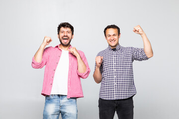 Obraz premium Portrait of a two joyful young men celebrating isolated over yellow background