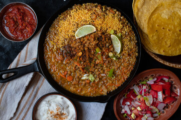 Vegan lentil stew in cast iron pan along with corn tortillas and side dishes