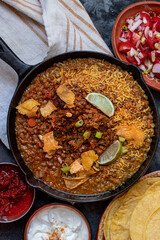 Vegan lentil stew in cast iron pan along with corn tortillas and side dishes