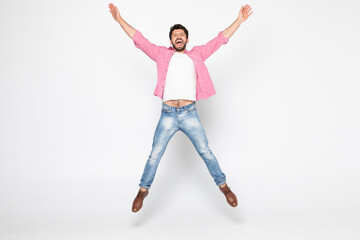 Excited young man jumping and smiling isolated on white background