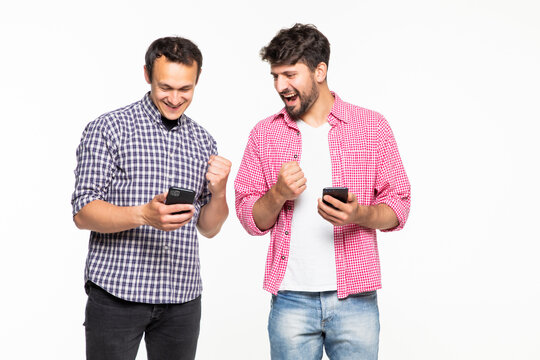 Portrait Of A Two Young Men Holding Mobile Phones With Win Gesture Isolated Over White Background