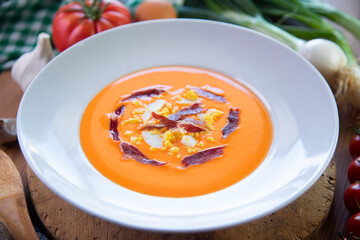 Traditional spanish Salmorejo. Cold tomato soup made with garlic, tomatoes, onion, bread and served with olive oil, iberico ham and boiled egg.