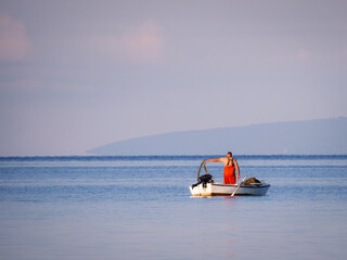 Fisherman in his boat throwing  his net into the water