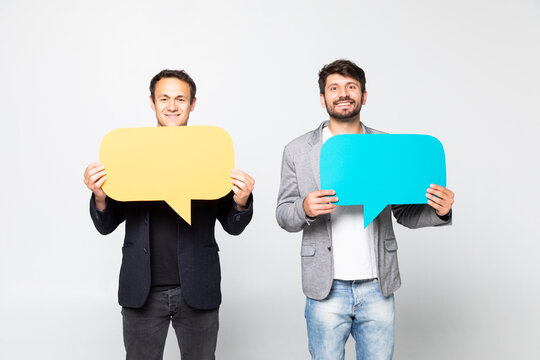 Portrait of a two satisfied business men holding empty speech bubbles isolated over white background