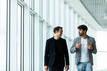 Portrait of two concentrated businessmen partners dressed in formal suit walking and having conversation during working meeting