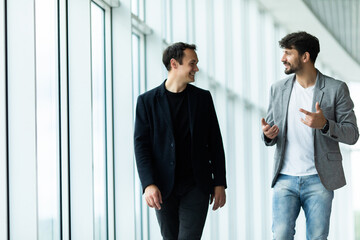 Portrait of two concentrated businessmen partners dressed in formal suit walking and having...