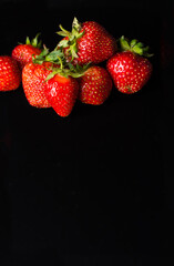A few ripe strawberries lie on a black background. Place for a copy of space