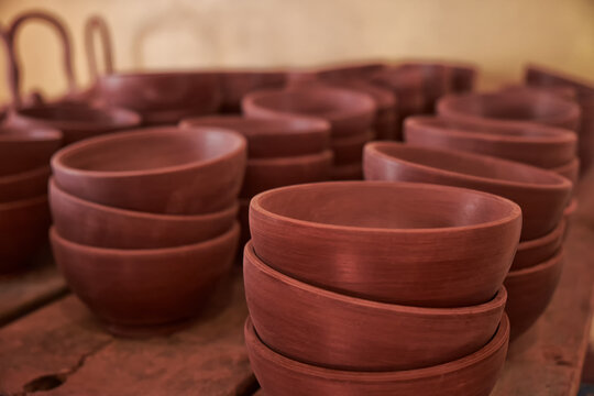 Clay pot close-up on potter's wheel. Inside interior. Wooden racks in pottery workshop in which there are pottery, many different pottery standing on the shelves in a potery workshop. Master crock.
