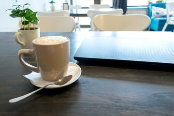 cup of coffee, latte, espresso and laptop for remote work on wooden table in cafe with copy space
