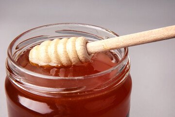 dipping wooden spoon into honey in glass jar