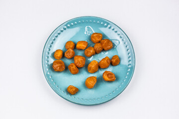 Orange candied kumquat on a turquoise plate.