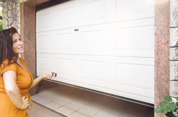 Garage door. Young woman holding remote controller and opening garage door