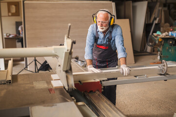 Portrait of an elderly carpenter using woodworking machine