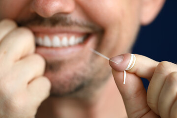 Smiling man is cleaning interdental space with dental floss. Oral health concept
