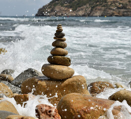 una torre de piedras redondas en una playa del mediterraneo