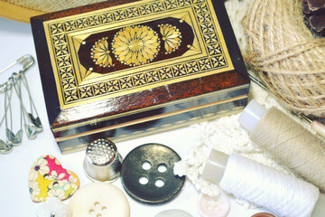 Sewing accessories in beige and ecru colours including vintage wooden box, sewing spools, buttons, jute cord. Scrapbooking and DIY. Hobby and needle work background. Retro style. 