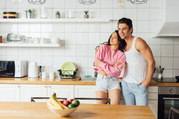 Selective focus of smiling man hugging beautiful woman near worktop in kitchen