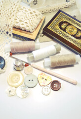 Fototapeta na wymiar Closeup of working place of tailor or fashion designer with cotton lace, vintage wooden box, sewing spools, buttons, crochet, linen fabrics. DIY, hobby, embroidery, needlework. Retro style