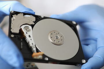 Gloved master holds hard drive away from computer. Maintenance and repair of computer equipment concept