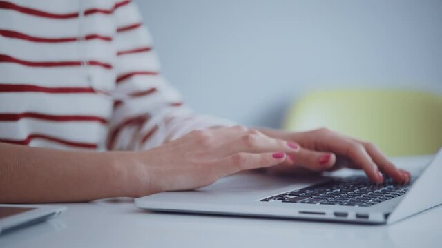 Close up of young female hipster hands working online on latop in bright work space. Remote work concept