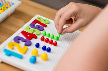 By provided numbers boy inserting pins. counting game. mathematical task. play at home. way of learning.