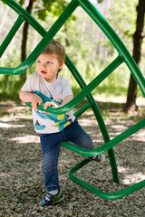 2-year old boy in a playground. summer day in the yard. child sliding down a slide. happiness of carefree childhood.