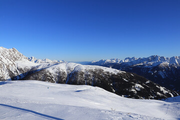 Obertilliach ski resort in west Austria in Tyrol. Panorama on Gailtal Alps with blue sky from top of Golzentipp. Scenery of ski slopes and snow mountains peaks