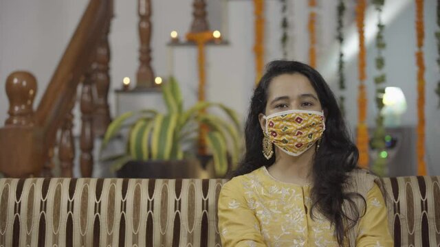 Indian girl in Indian ethnic attire wearing Coronavirus protection mask, getting ready for Indian Festival- Raksha Bandhan, enjoying.