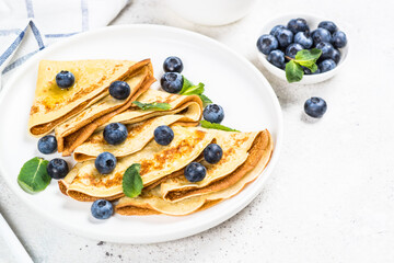 Crepes with blueberries at white table.