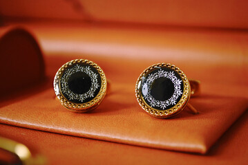 Black silver gold contrast round cufflink suit buttons isolated on leather with soft focus background,men formal luxury fashion clothing jewelry.