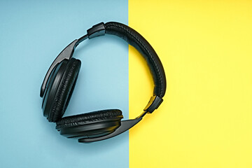 Large, black headphones lie on a colored background. Device for individual listening to music.