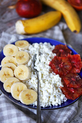Selective focus. A healthy dessert or snack with cottage cheese and fruits. Cottage cheese with banana and orange on a plate. The keto diet.