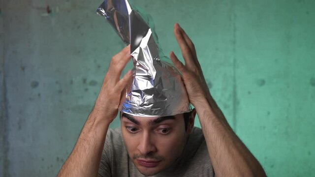 Insane young man wearing a tin foil cap because he is afraid of the waves and the government spying on him.He is scared.